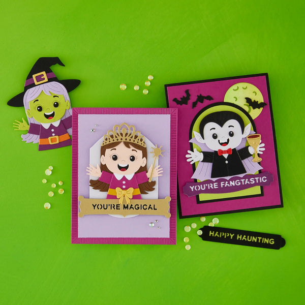 Three handmade Halloween-themed paper cutout cards arranged on a bright green background, including a witch, a princess, and a vampire, with small scattered decorative beads.