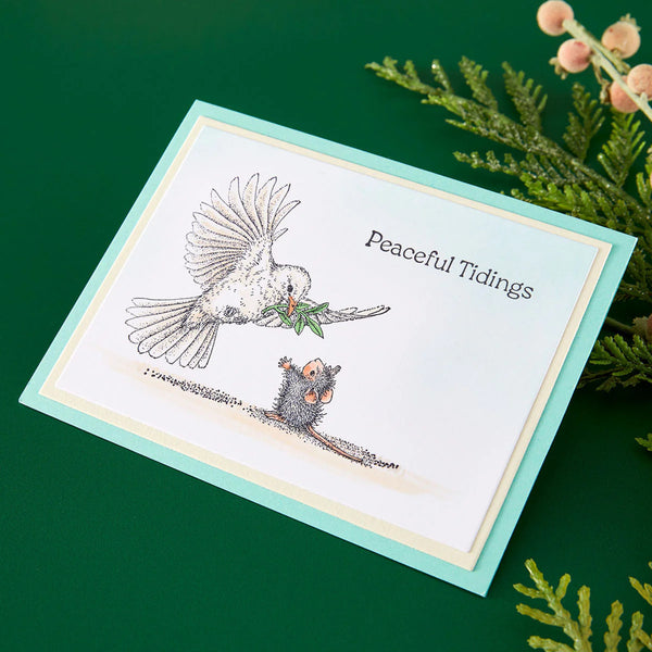 Greeting card with illustrations of a bird and mouse, and 'Peaceful Tidings' text, on a green background.