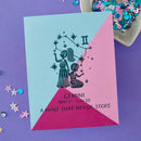 Card with Gemini zodiac design on a purple background with decorative elements.