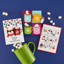 A flat-lay of Christmas-themed greeting cards and marshmallows on a dark blue background. The cards feature festive illustrations including penguins in hot cocoa mugs, snowflakes, holiday stockings, and marshmallows, with one card reading 'YOU'RE THE COCOA TO MY MARSHMALLOW'.