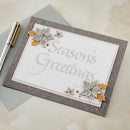Season's Greetings card with decorative flowers on a textured surface