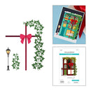 A collage showing a holiday-themed card design and its packaging: a large flat illustration of a red cross with green ivy vines and a pink bow, a small streetlamp graphic, and two smaller photos of the assembled card and printed card package on a white background.