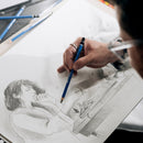 Person drawing a detailed sketch of a person with a pencil on a white sheet of paper.