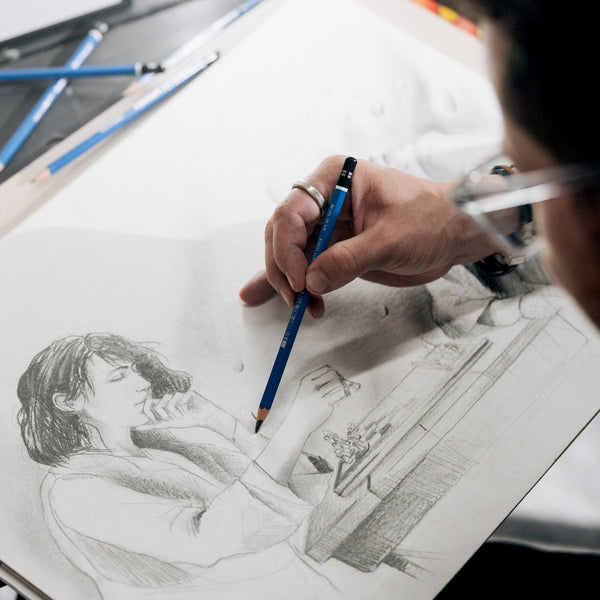 Person drawing a detailed sketch of a person with a pencil on a white sheet of paper.