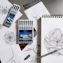 Art supplies including markers, pens, and a notebook with artistic drawings on a gray surface.
