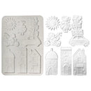 White silicone baking mold set featuring a rectangular tray with whimsical embossed designs like a sun, a child, a car, and houses, alongside eight individual house-shaped mold cavities on a plain white background.