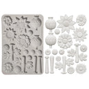 A white silicone craft mold with floral and vase-shaped cavities, shown next to multiple matching white embossed paper or clay applique pieces on a plain white background.