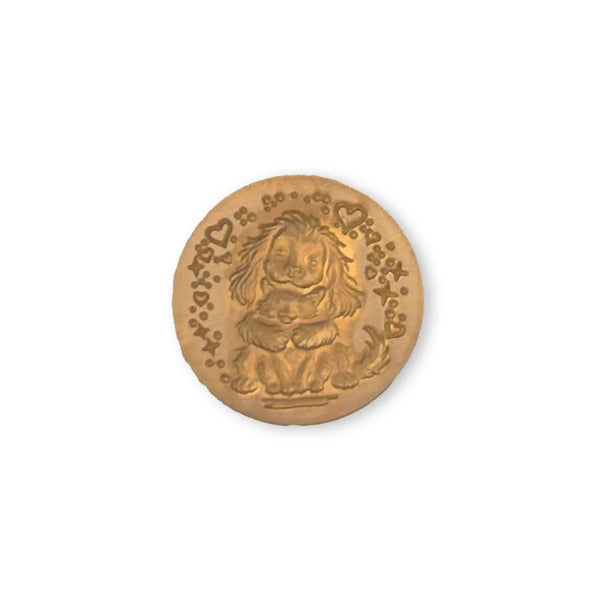 A round, gold-toned metal button featuring an embossed cartoon lion sitting in a seat, surrounded by small hearts and decorative patterns.
