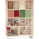 A sheet of scrapbooking paper featuring a Christmas village theme, with a rustic framed illustration of a snowy cabin, a red bow, and multiple patterned and decorative paper/cutout sections.