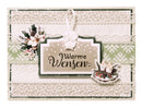 A handmade Christmas greeting card with the German text 'Warme Wensen' (meaning 'Warm Expectations') in black script on a beige tag. The card features a layered design with cream and sage green textured paper, lace borders, a white hanging ribbon, a floral accent on the left, and a miniature snow-covered gift box on the right.