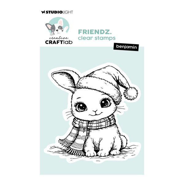 A clear stamp product package featuring a black-and-white line drawing of a bunny wearing a Santa hat and striped scarf on a pale blue panel, with Studio Light branding, the text 'FRIENDZ. clear stamps', and the name benjamin.