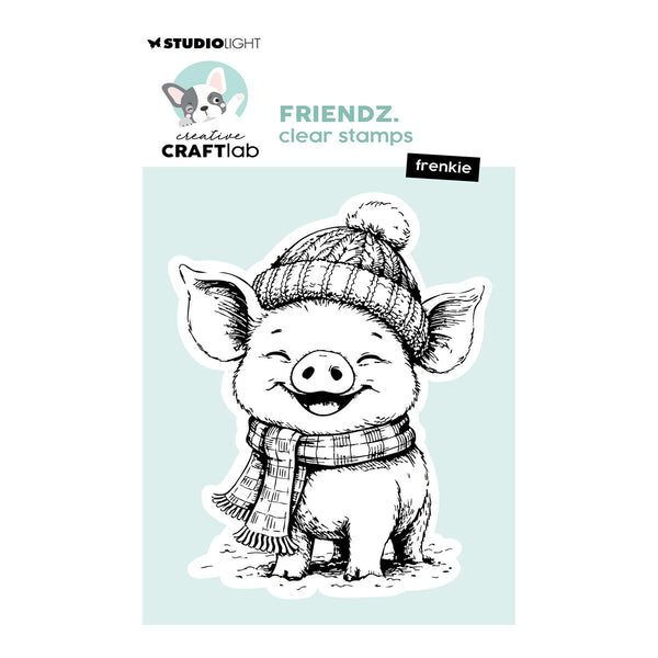 Studio Light Creative Craftlab 'frenchie' clear stamp packaging featuring a black and white line art illustration of a smiling pig wearing a plaid beanie and scarf, set against a light blue background.