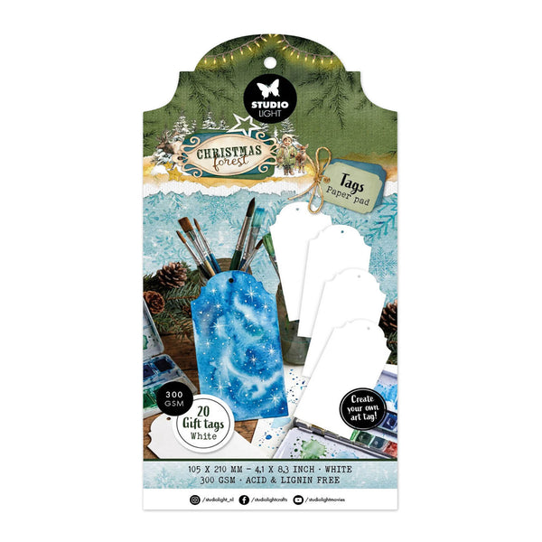 Studio Light Christmas 2025 gift tags set in white, displayed on its original retail packaging card. The packaging features festive holiday graphics including pine trees, pinecones, and watercolor paintbrushes.
