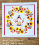 Card with a teapot design surrounded by sunflowers and leaves on a wooden surface