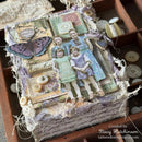 A handmade vintage-style mixed media art box decorated with layered paper collage, a purple butterfly, buttons, lace, and ribbons, displayed inside a wooden drawer alongside other decorative craft items. A watermark in the bottom right corner reads 'Created by Stacy Hutchinson tatterednestdesigns'.