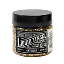 A jar of Tim Holtz Distress Liquid Tinsel chunky glitter in the 'Antiqued' shade, featuring a black lid and a black-and-white label, shown on a plain white background.