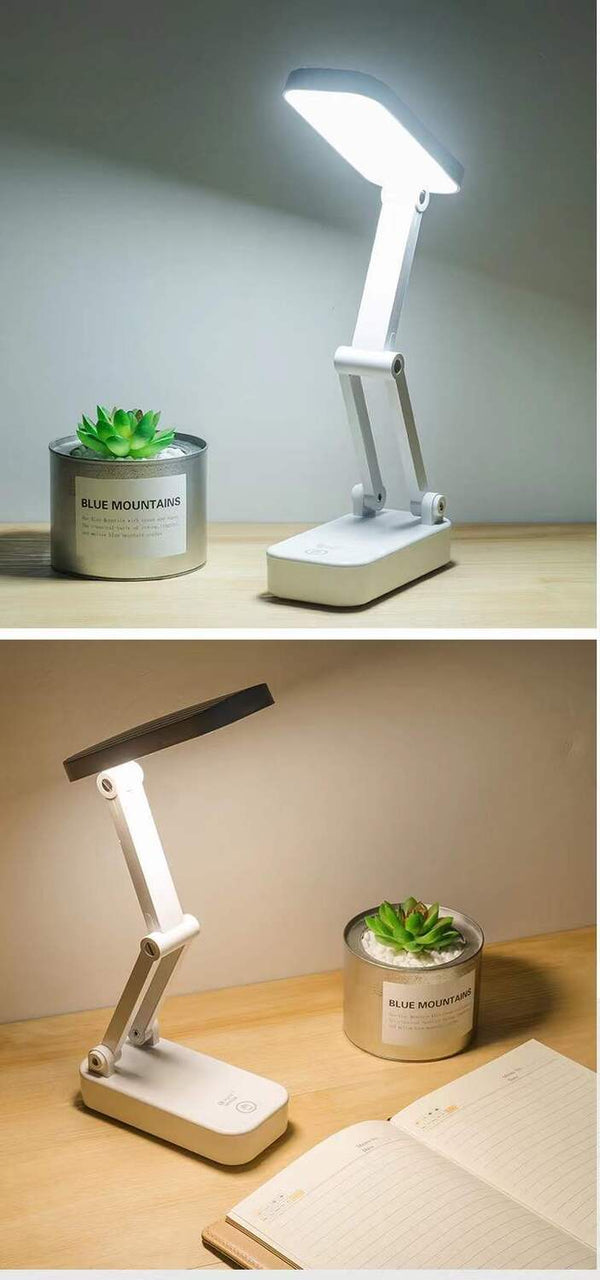 Foldable desk lamp on a wooden surface with a small plant and notebook.