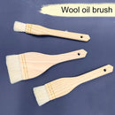 Three wooden-handled wool oil brushes arranged diagonally on a dark blue background, with a cream paint stroke graphic and the text 'Wool oil brush' at the top.