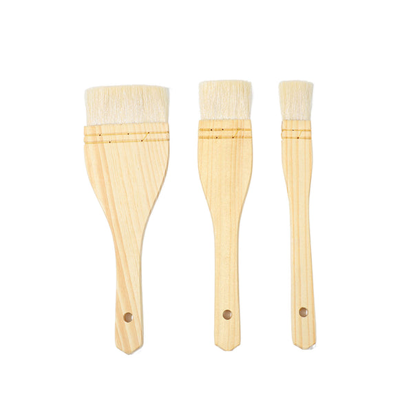 Three wooden paint brushes in different sizes arranged vertically on a plain white background.