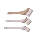 Three small angled paint brushes with light natural wood handles and off-white bristles, arranged vertically on a plain white background.