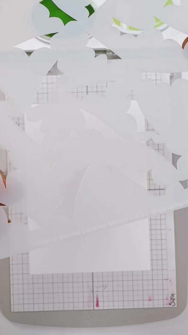 White layered paper cutout sheets with scalloped edges layered over a gray gridded cutting mat.