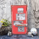 A handmade red Christmas greeting card with four photo frames, displayed on a rustic gray wood background with pinecones, greenery, and silver ornaments.