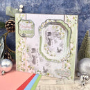 A handmade Christmas greeting card with a snowy winter scene, layered scalloped frames, floral borders, and text reading 'Christmas is filled with joy' and 'Christmas Magic,' styled with holiday ornaments and greenery against a textured blue backdrop.