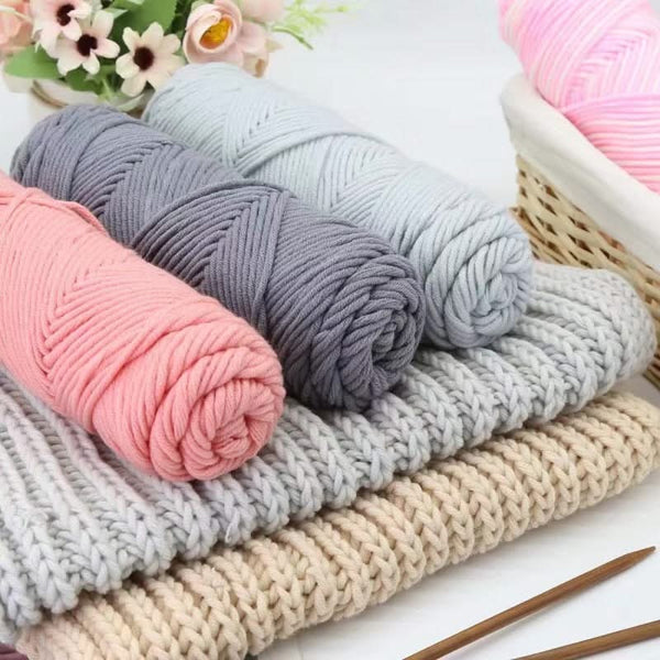 Stack of colorful yarn rolls with knitting needles on a white background